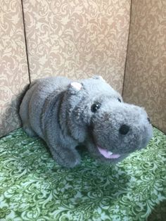 a stuffed hippo laying on top of a green and white chair next to a wall