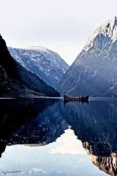 a boat floating on top of a lake surrounded by mountains