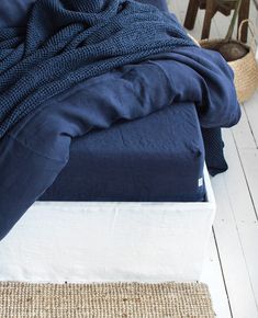 an unmade bed sitting on top of a wooden floor next to a basket filled with plants