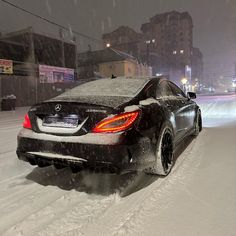 a black car driving down a snow covered street