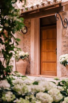 a wooden door sitting next to two large vases with white flowers on it's side