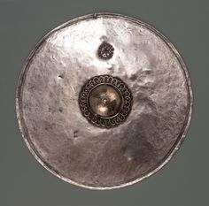 a silver plate with an ornate design on the top and bottom, sitting on a gray surface