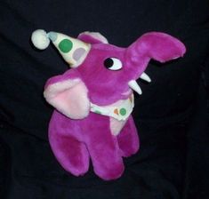 a pink stuffed animal with a party hat on it's head and eyes, sitting in front of a black background