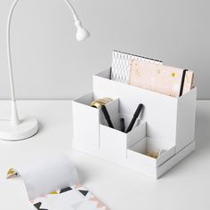 a white desk with some pens and paper on it next to a lightbulb