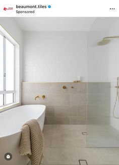 a white bath tub sitting next to a shower in a bathroom under a large window