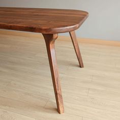 a wooden table sitting on top of a hard wood floor next to a white wall