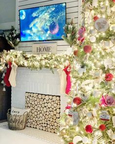 a decorated christmas tree in front of a fireplace with a flat screen tv above it