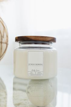 a white candle sitting on top of a table next to a wooden container with a brown lid