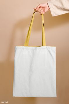 a person holding a white bag with yellow handles