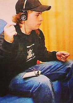 a young man sitting on top of a blue couch wearing headphones