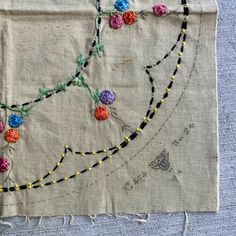 a piece of cloth with flowers on it and some thread hanging off the side of it