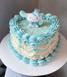 a blue and white cake with an animal decoration on it's top, sitting on a plate