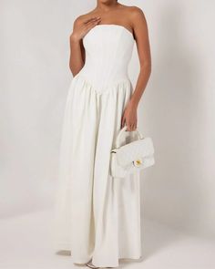 a woman in a white dress holding a purse