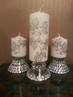 three white candles sitting on top of a table next to some crystal balls and a candle holder