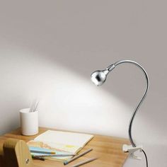 a desk with a lamp on top of it next to a cup and pencils