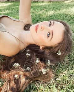 a woman laying on the grass with flowers in her hair