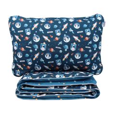 the blue space themed pillow case is folded on top of it and has an image of rockets