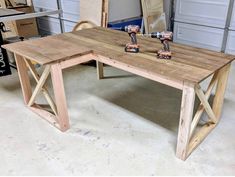 a wooden table sitting in a garage next to two drillers on top of it