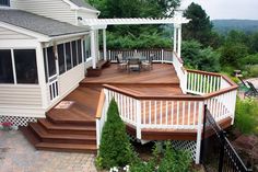 a wooden deck with white railings next to a house