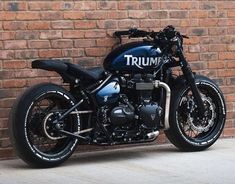 a triumph motorcycle parked in front of a brick wall