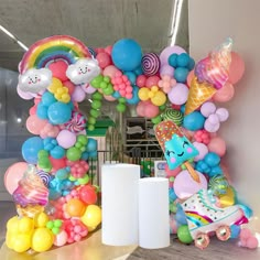 an arch made out of balloons and other items is displayed in front of a wall