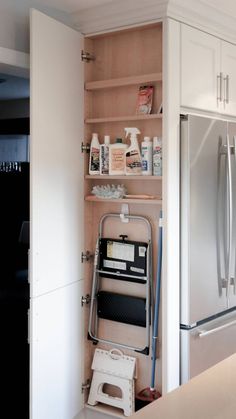 a kitchen with white cabinets and stainless steel refrigerator freezer combo in the corner, next to an open pantry door