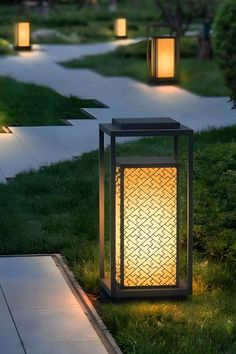 some lights that are in the grass near a sidewalk and walkway path with green grass on both sides