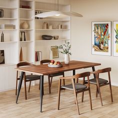 a dining room table with two chairs and a vase on top of it in front of bookshelves