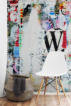 a white chair sitting in front of a wall covered in colorful graffiti letters and shapes