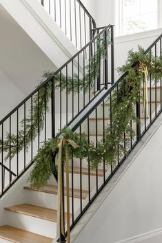 wreaths tied to the banister rail and stairs in a home decorated for christmas