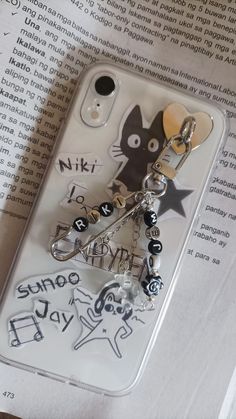 a cell phone case with a cat and star charm attached to it, sitting on top of an open book