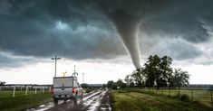 a truck driving down a road under a large tornado