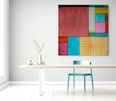 a dining room table with two chairs and a painting hanging on the wall above it