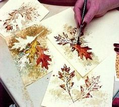 someone is painting leaves on paper with watercolors