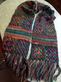 a multicolored scarf with fringes sitting on top of a table