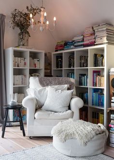 a living room filled with furniture and bookshelves next to a white rug on top of a hard wood floor