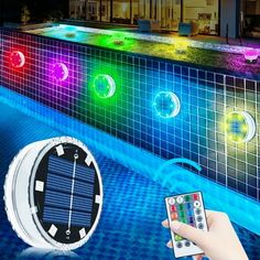 a person holding a remote control next to a pool with colorful lights on the side