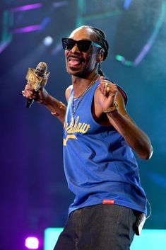 a man holding a microphone in his right hand and wearing sunglasses on top of him