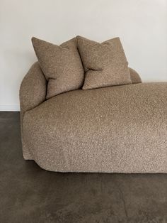 a couch with two pillows on top of it in front of a wall and floor