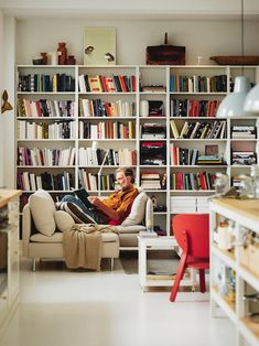 a man sitting on a couch in front of a bookshelf filled with lots of books