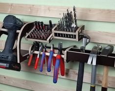 there are many different tools hanging on the wall and organized with pegs to hold them