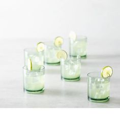 four shot glasses filled with limeade and lemon wedges on a white countertop