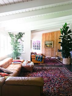 a living room with couches and rugs in front of large windows on the wall