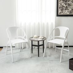 two white chairs sitting next to each other in front of a window