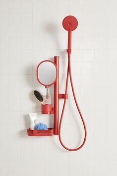 a red shower head mounted to the side of a white wall next to a mirror