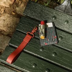 a cell phone case sitting on top of a green bench next to a red lanyard