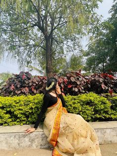 a woman sitting on the ground talking on her cell phone while wearing a sari