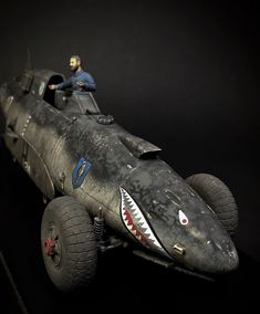 a toy model of a shark car with a man sitting on it's side