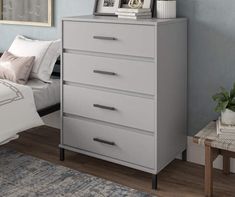 a white chest of drawers in a bedroom with pictures on the top and bottom shelf