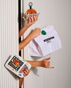 two people holding up donuts in front of a wall with stickers on it